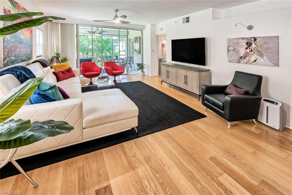 Living room featuring light hardwood / wood-style floors, ceiling fan, and a wall of windows