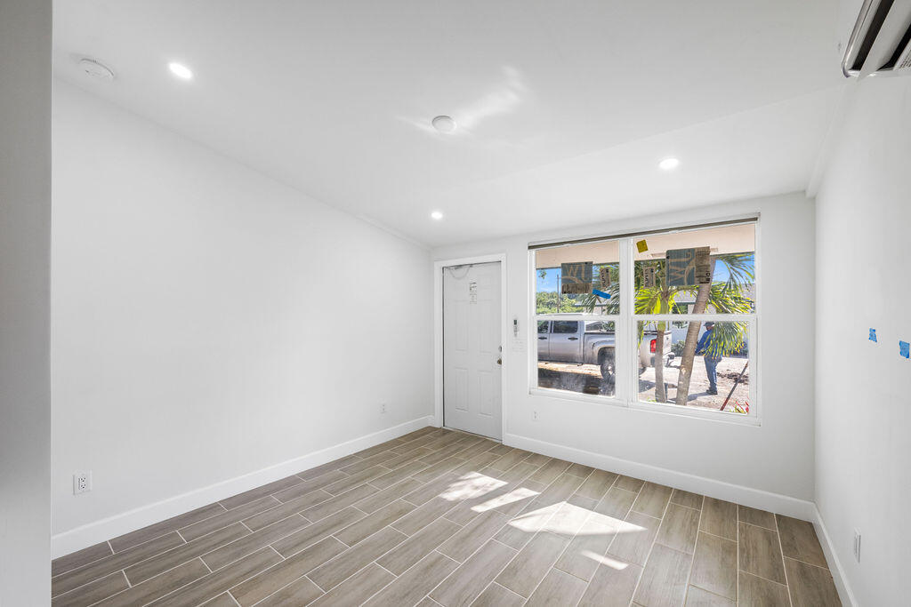 a view of an empty room with a window and wooden floor