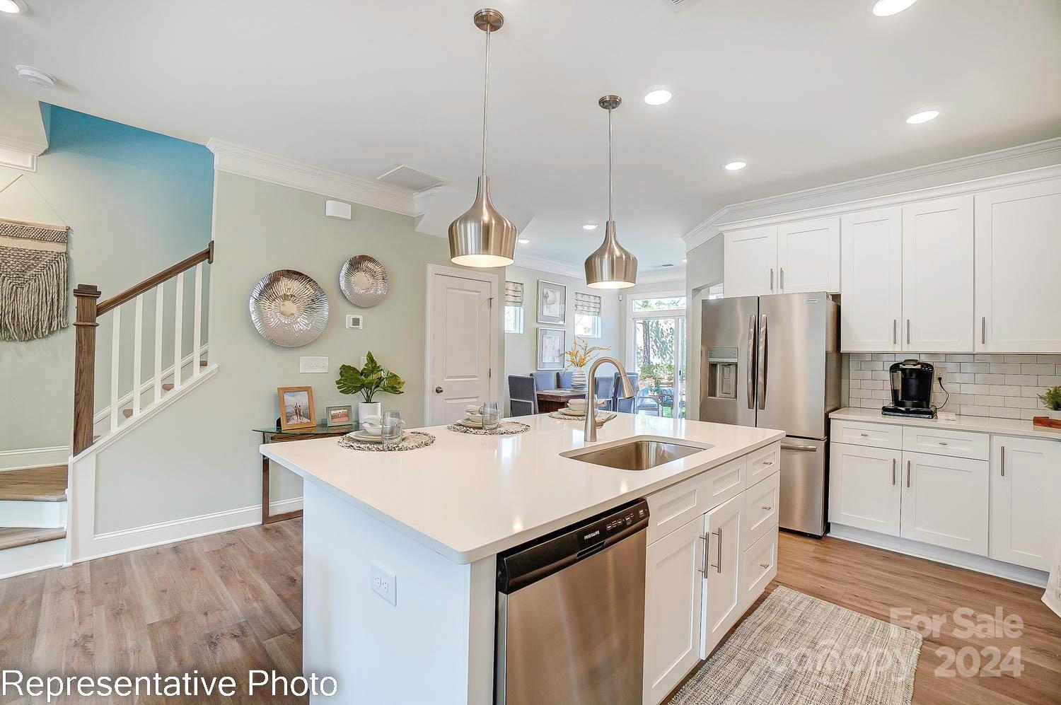 a kitchen with a sink a stove a refrigerator and white cabinets with wooden floor