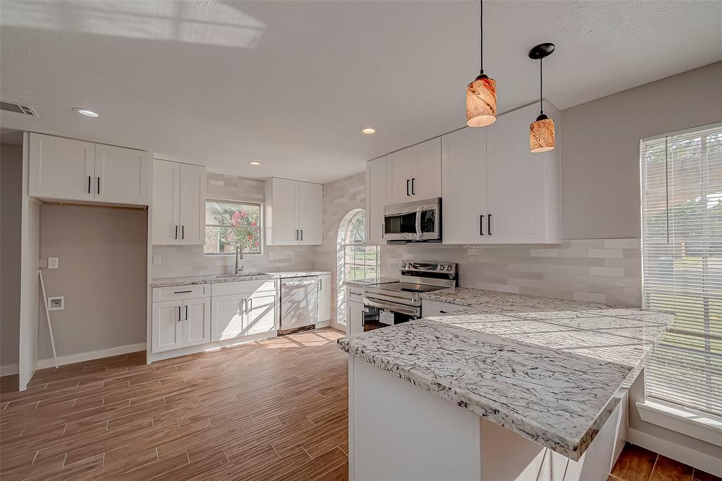 a kitchen with stainless steel appliances granite countertop a sink dishwasher stove and refrigerator with wooden floor