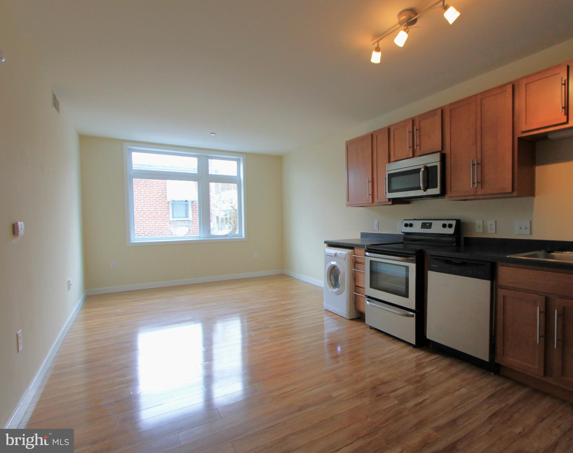 a kitchen with granite countertop wooden floors a stove and a microwave