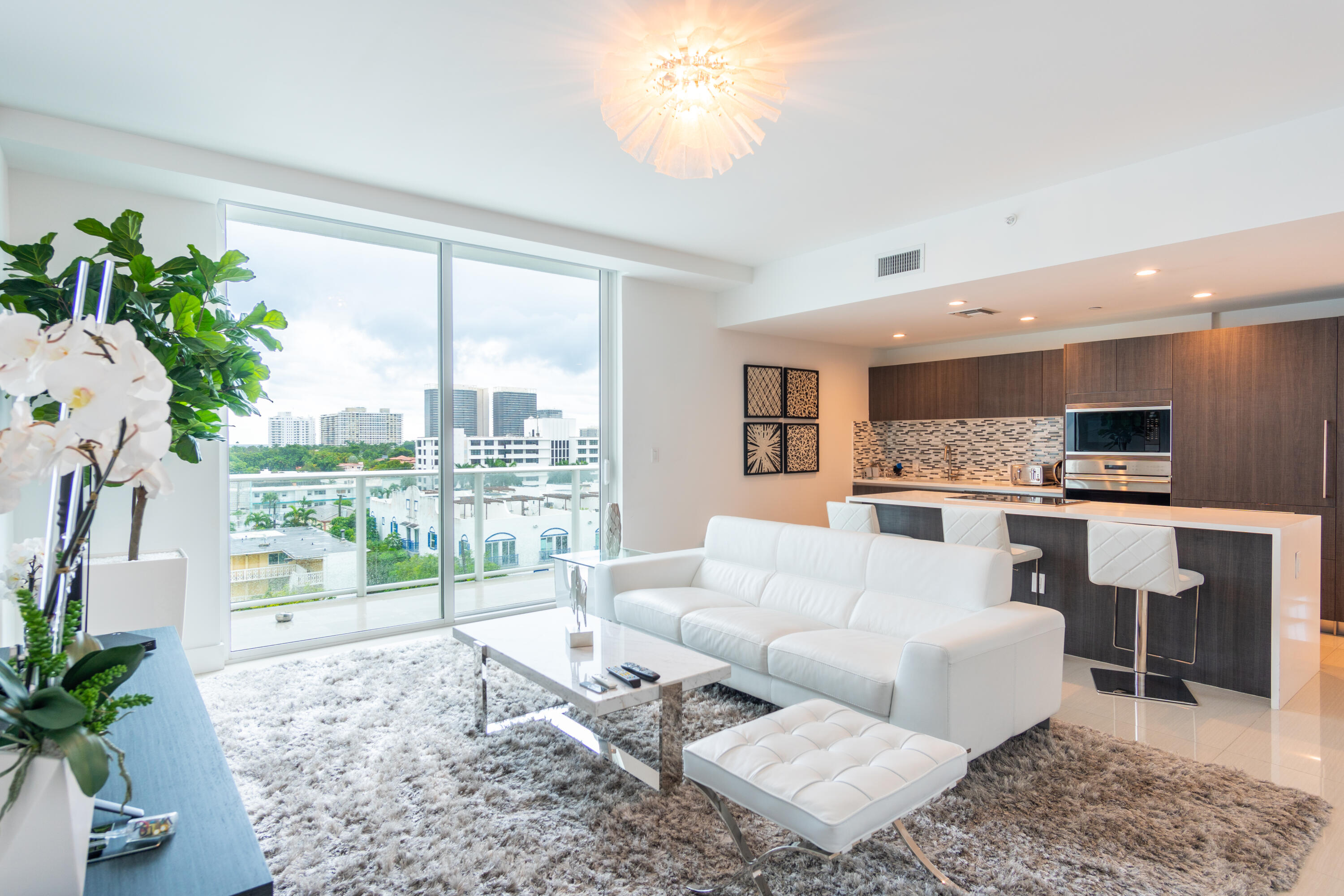 a living room with furniture and a large window with kitchen view