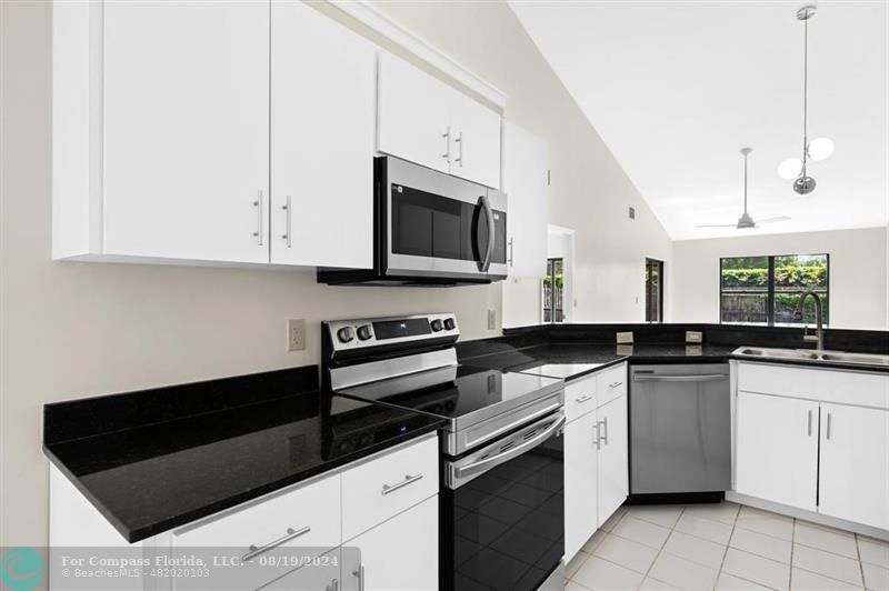 a kitchen with granite countertop white cabinets and white appliances