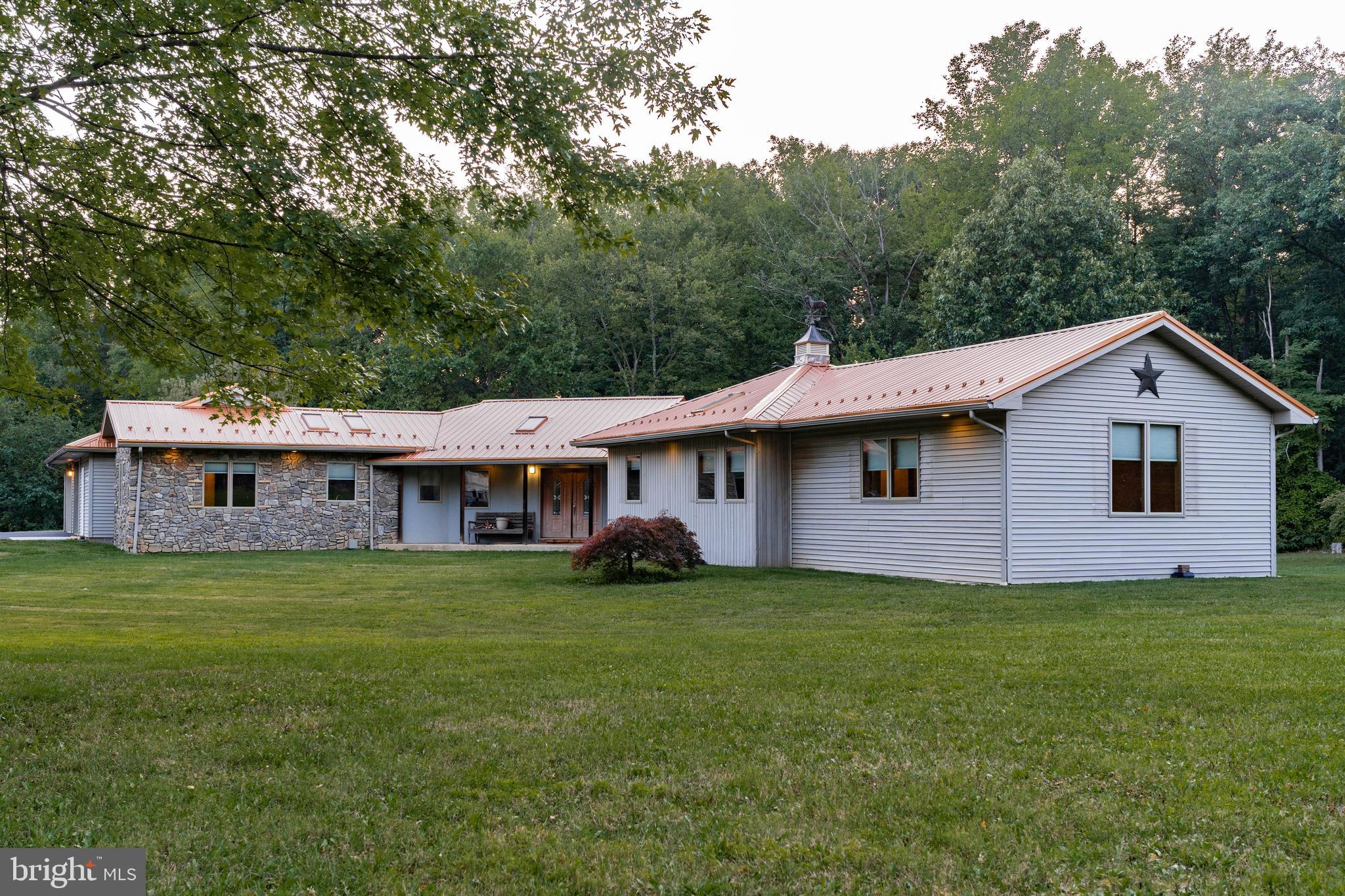 a house that is sitting in the grass with large trees