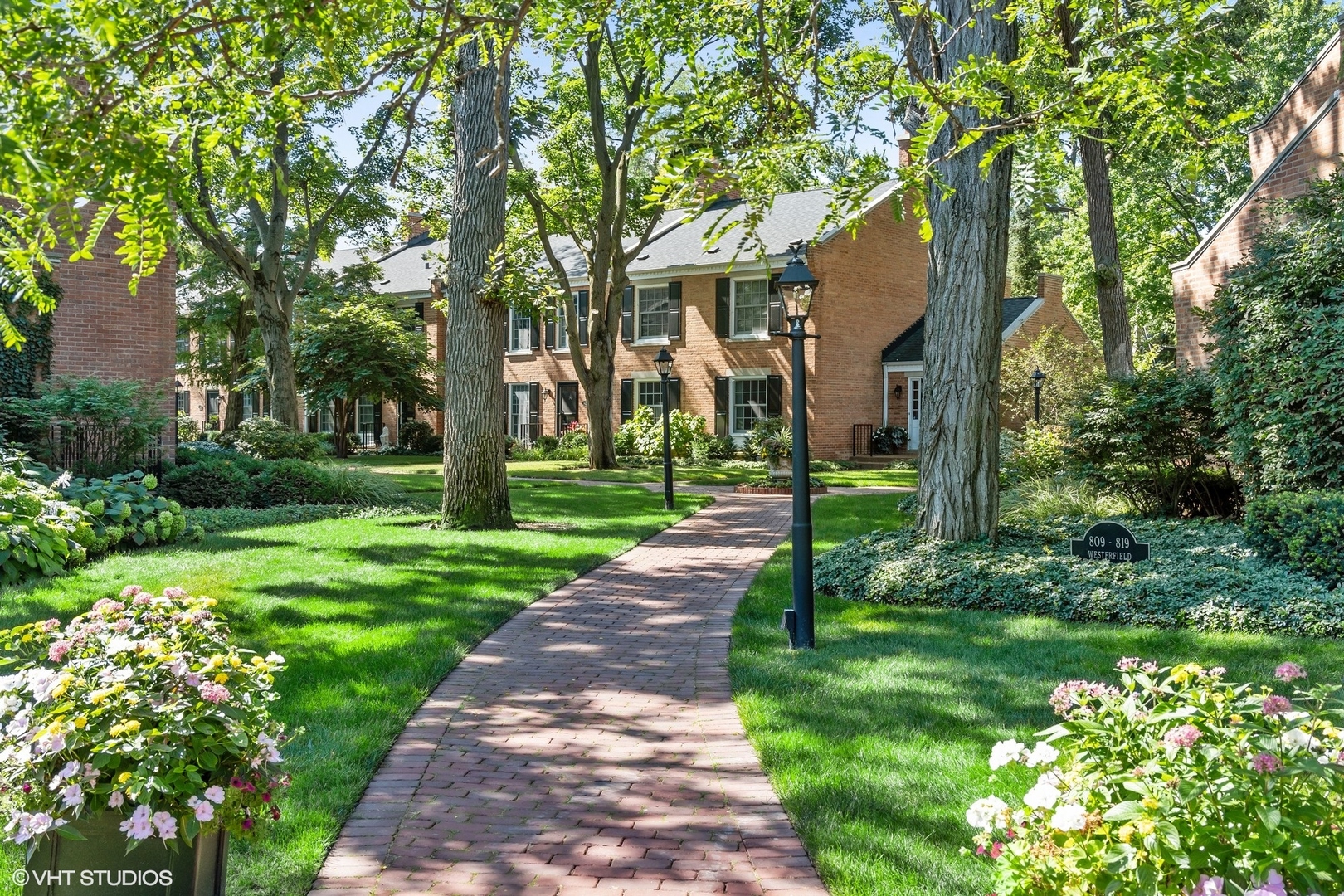 a view of a white house next to a yard with big trees