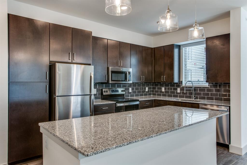 a kitchen with stainless steel appliances granite countertop a sink a refrigerator and a stove