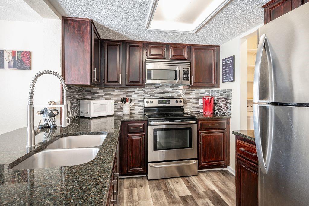 a kitchen with stainless steel appliances granite countertop a stove refrigerator and microwave