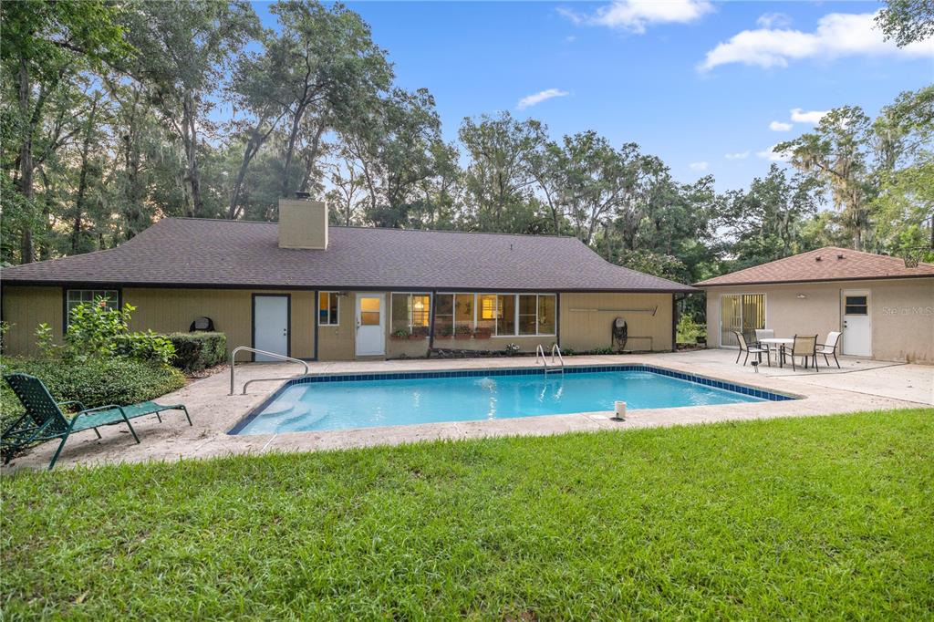 a view of house with swimming pool and a yard