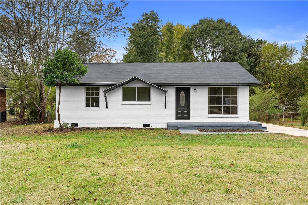 a house that has a big yard with plants and trees in front of it