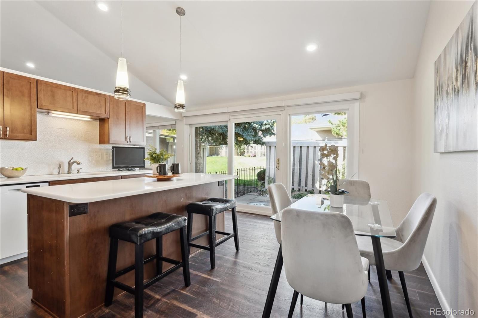 a dining room with stainless steel appliances granite countertop a sink a stove a table and chairs