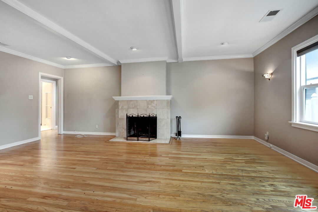 a view of empty room with wooden floor and fireplace