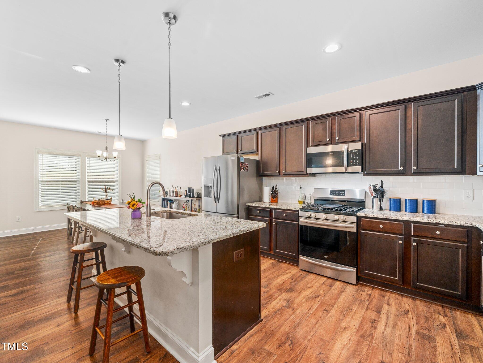 a kitchen with stainless steel appliances granite countertop a sink a stove and a wooden floors