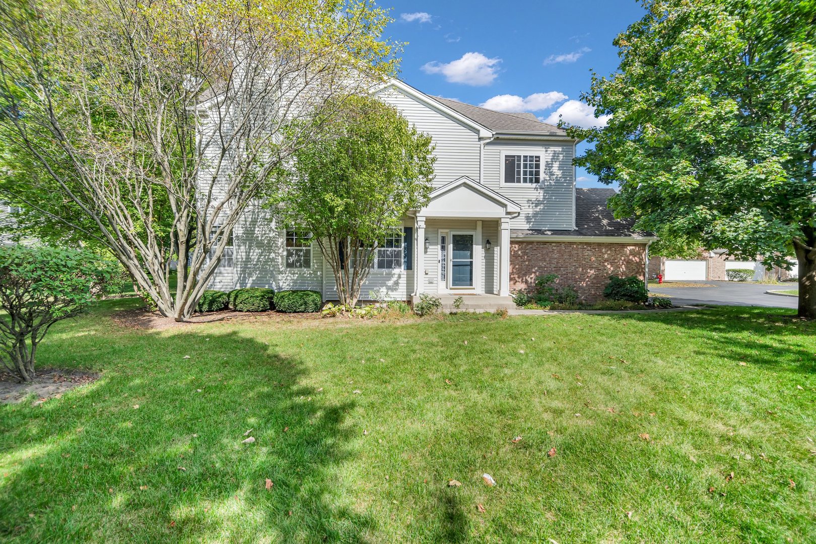 a front view of a house with a yard and a tree