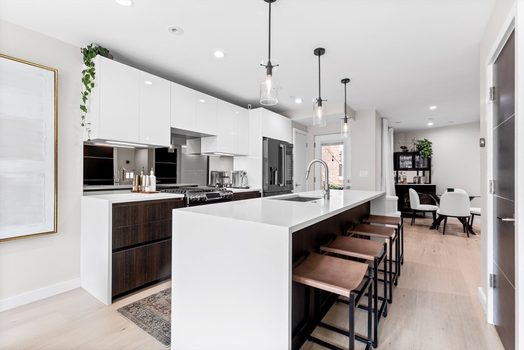 a kitchen with stainless steel appliances kitchen island granite countertop a table chairs and a refrigerator