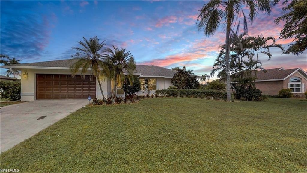 View of front of home with a lawn and a garage