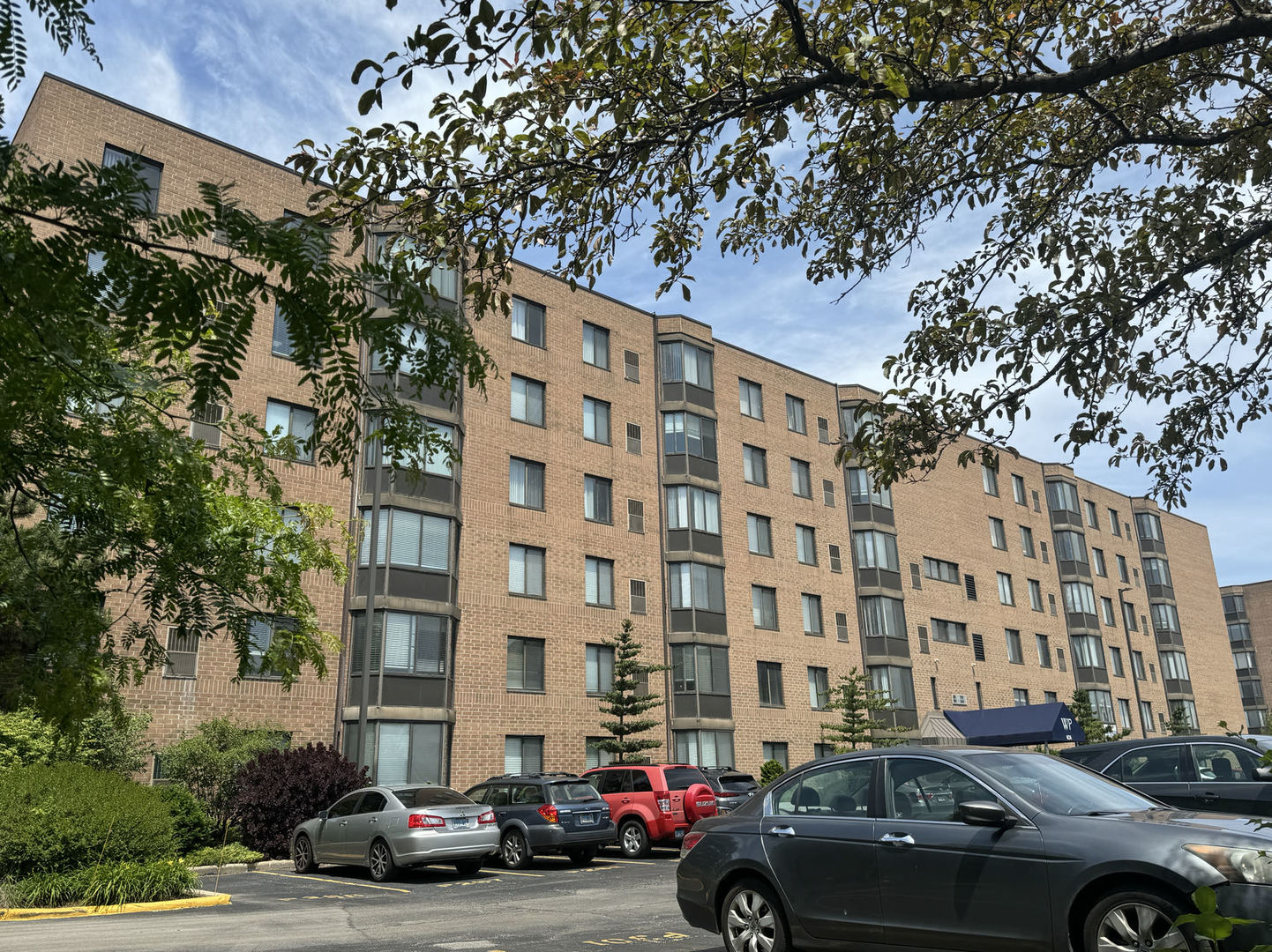 front view of a building with lot of cars parked on the roadside