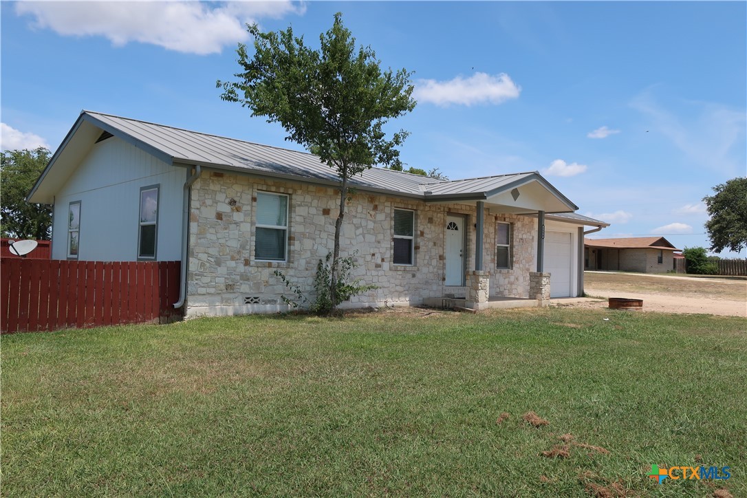 a front view of house with yard and trees in the background