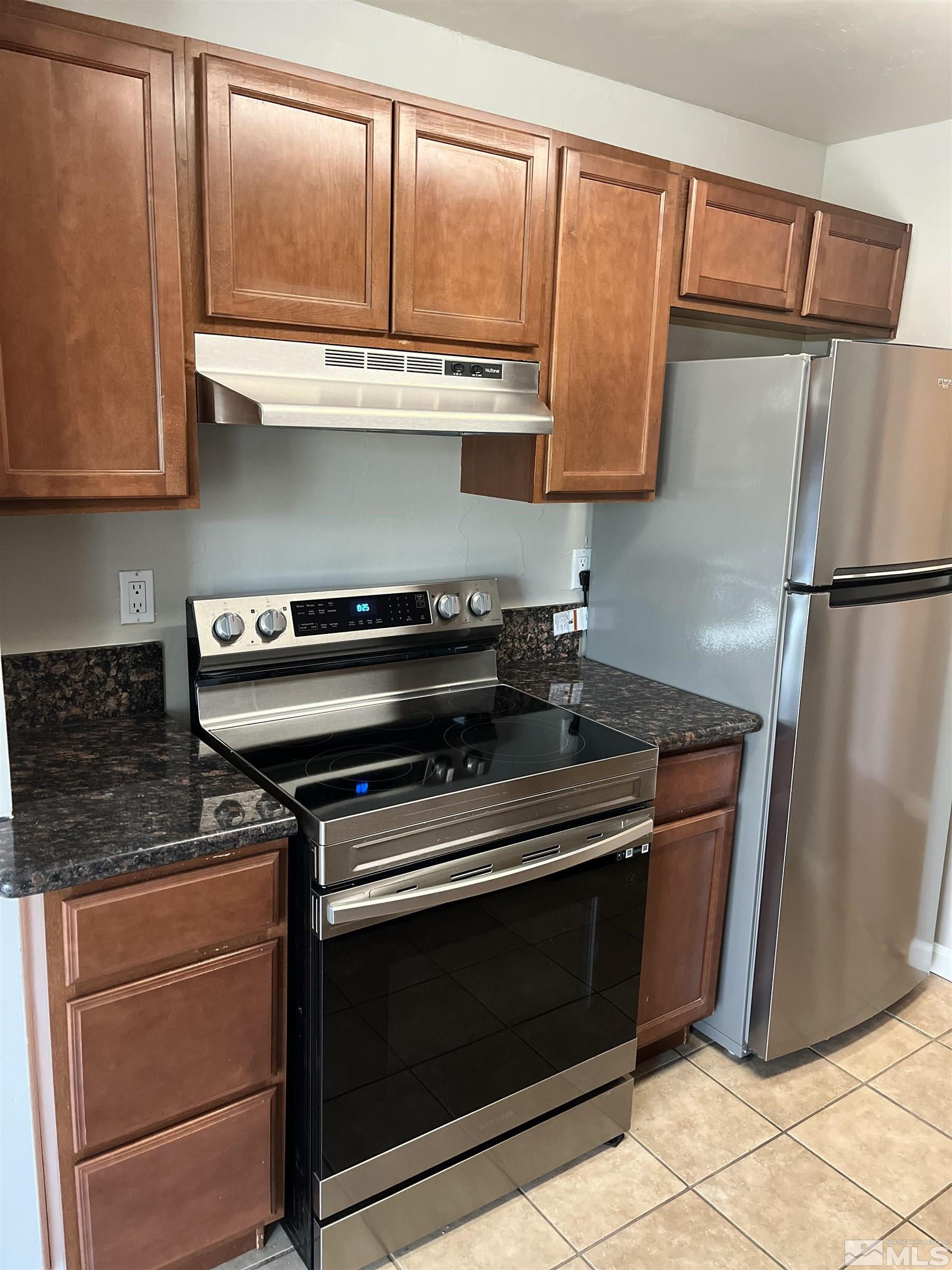 a kitchen with granite countertop a refrigerator stove and cabinets