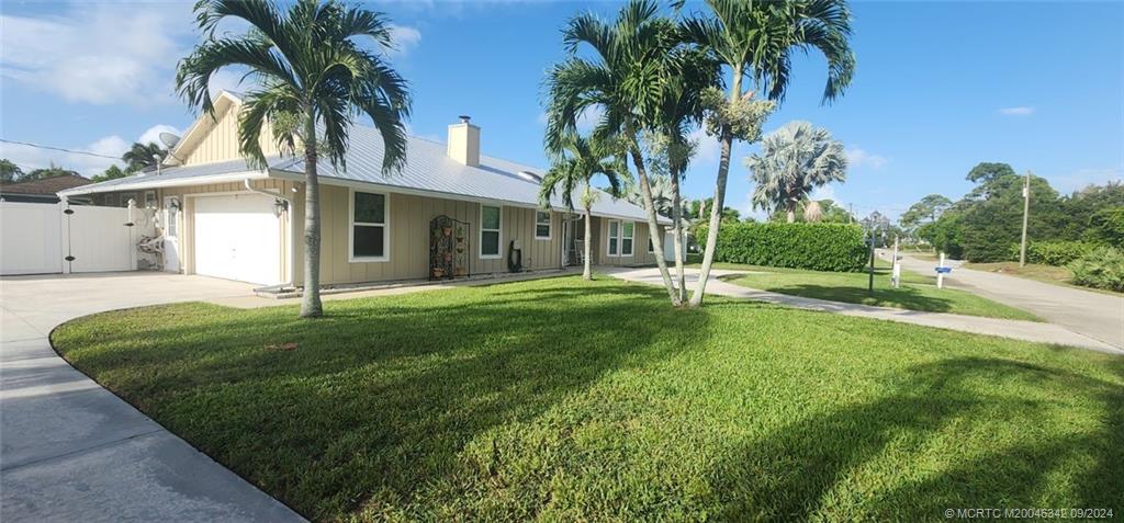 a view of a white house with a big yard and palm trees