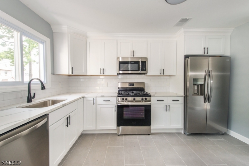 a kitchen with stainless steel appliances white cabinets a sink and a window