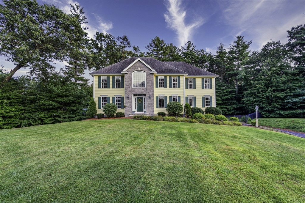 a front view of a house with a yard and trees