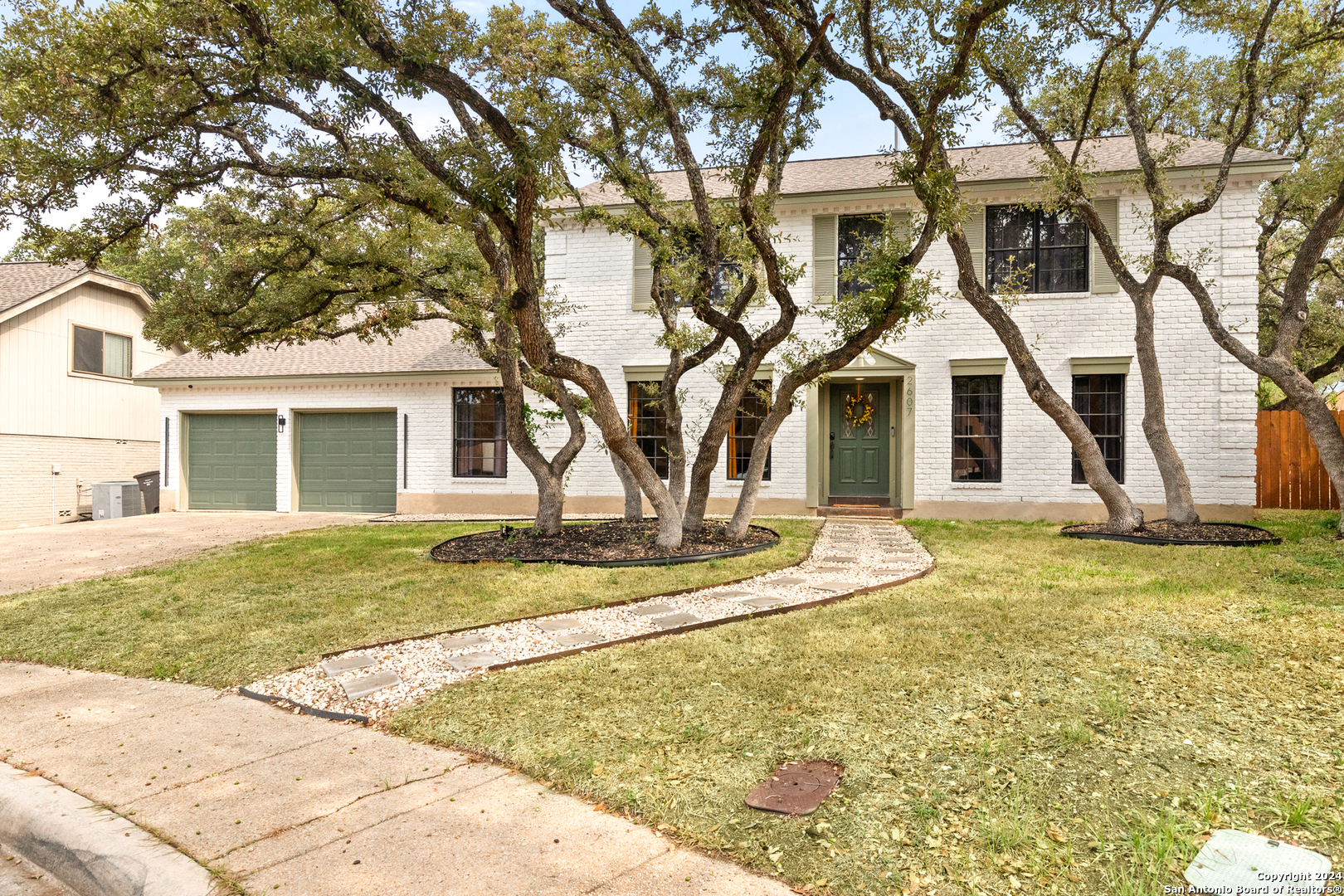 a view of a yard in front of a house with a large tree