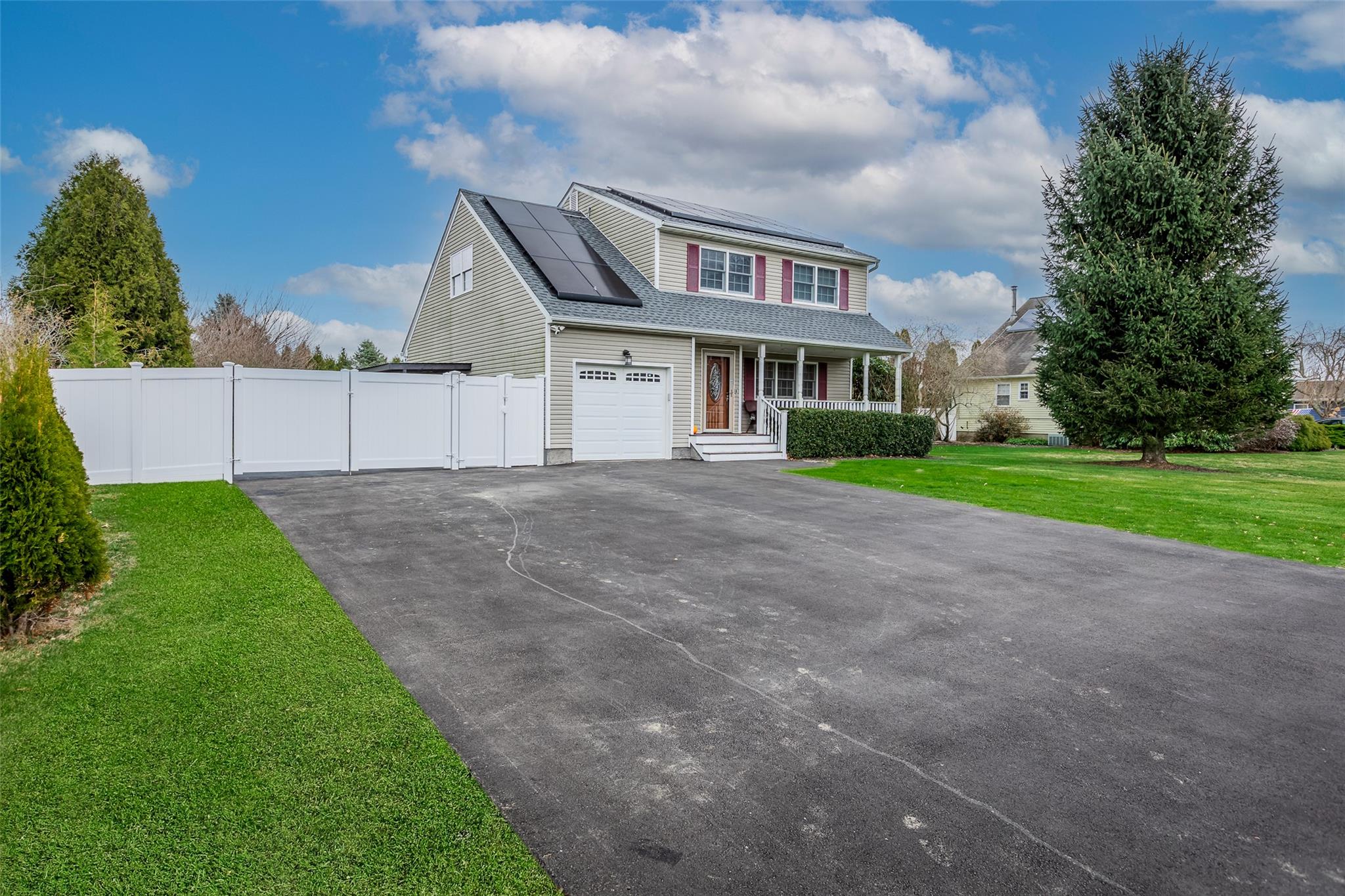 Front of property featuring solar panels, covered porch, and a front lawn