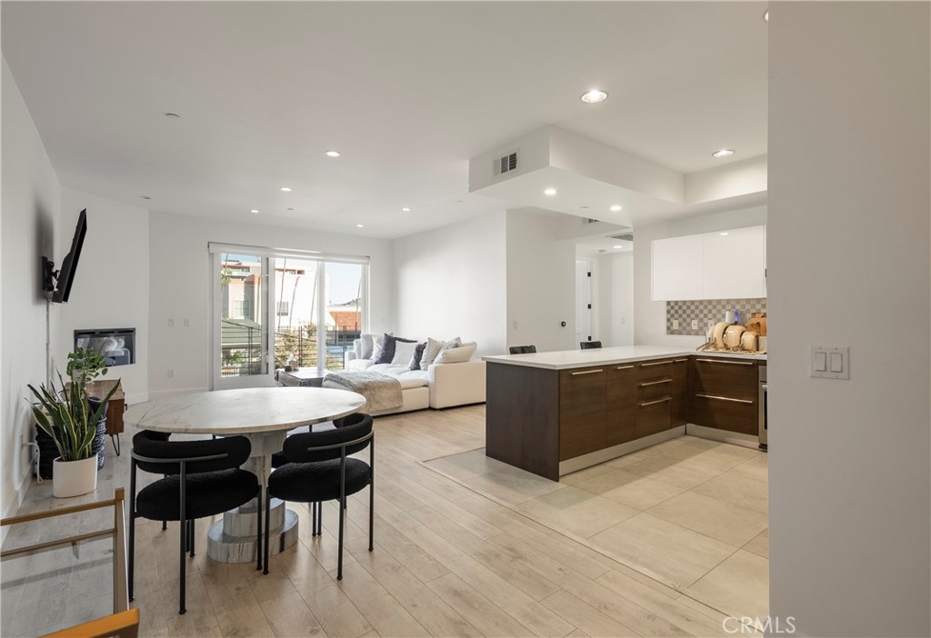 a living room with furniture a wooden floor and a kitchen