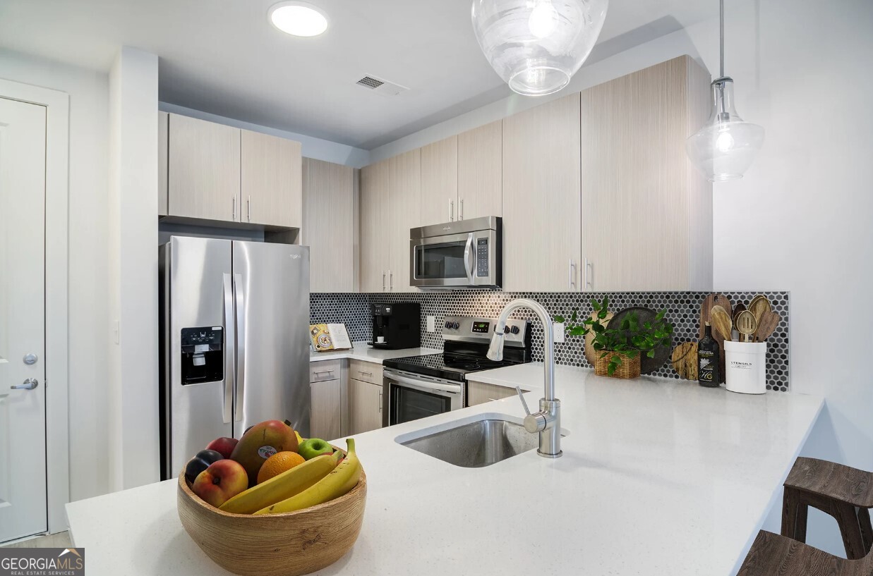 a kitchen with stainless steel appliances granite countertop a sink a stove and a refrigerator