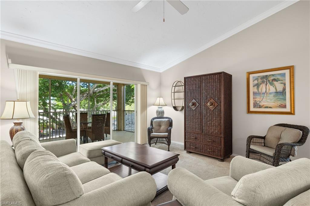 Living room featuring crown molding, vaulted ceiling, ceiling fan, and light colored carpet