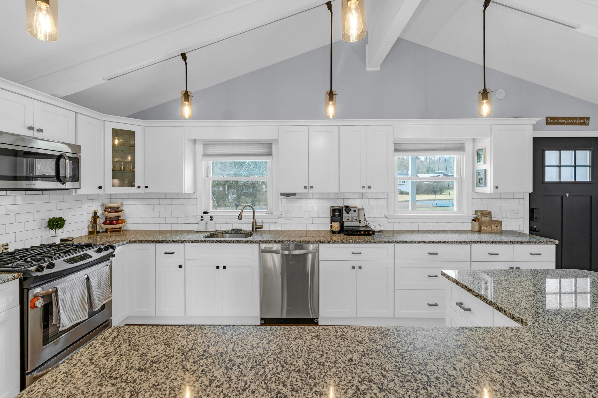 a kitchen with granite countertop a sink a counter space appliances and cabinets