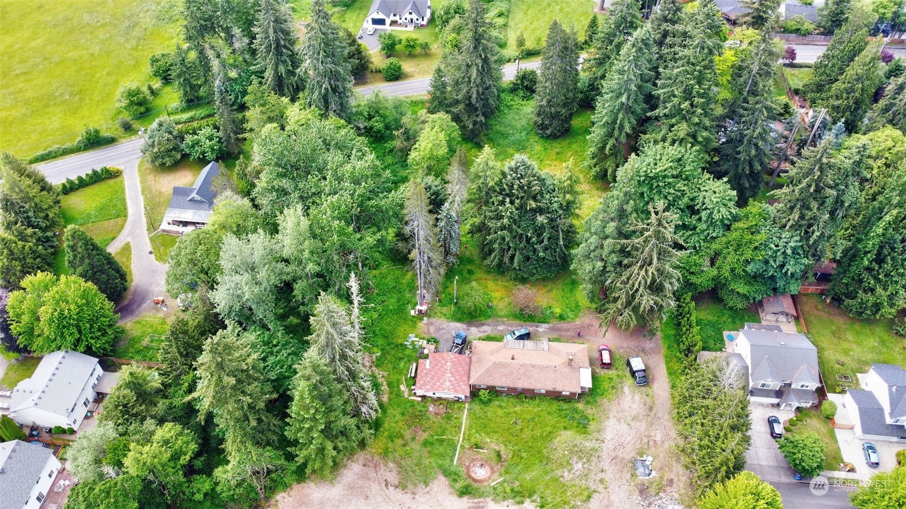 an aerial view of residential house with outdoor space and trees all around