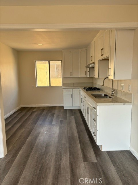 a kitchen with a sink a stove cabinets and wooden floor