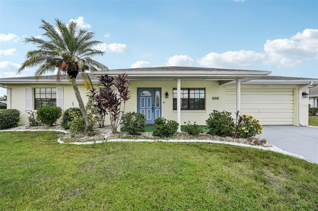 a front view of a house with a yard and palm trees