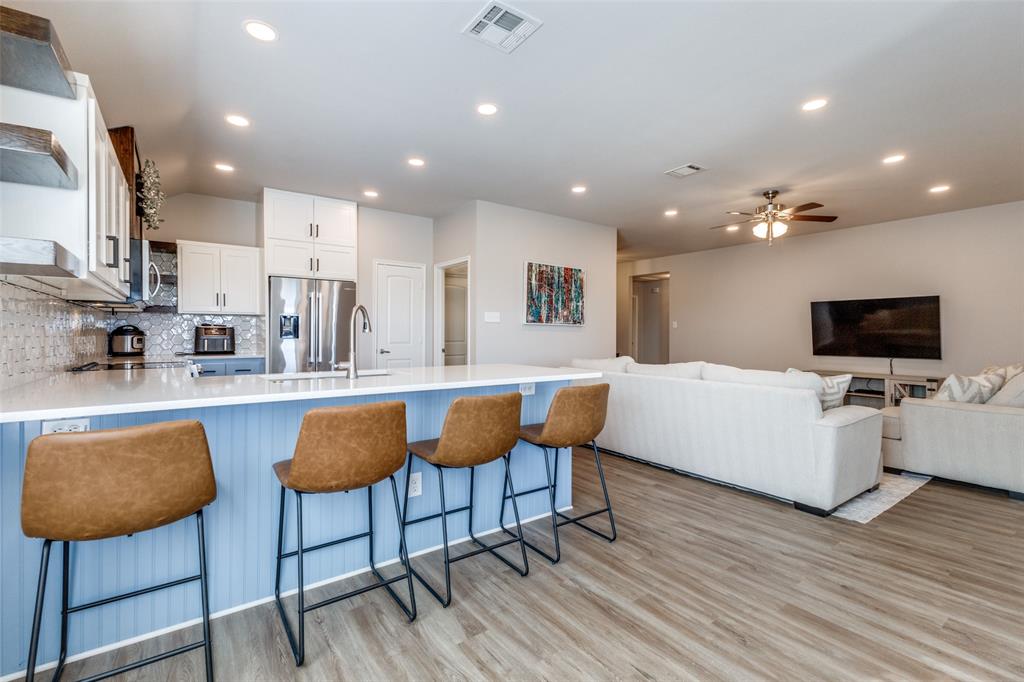 Kitchen featuring a kitchen breakfast bar, appliances with stainless steel finishes, ceiling fan, white cabinets, and light hardwood / wood-style floors