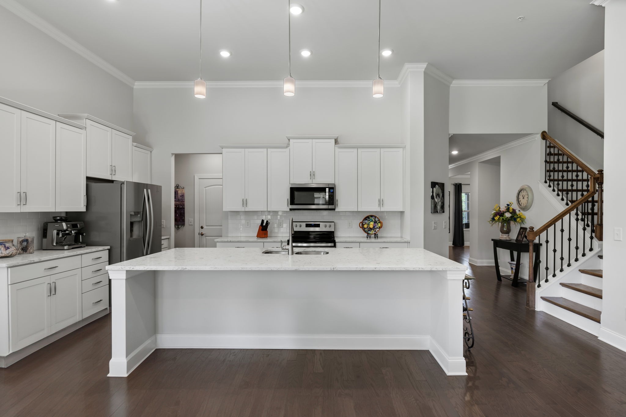 a large white kitchen with lots of counter space a sink appliances and cabinets