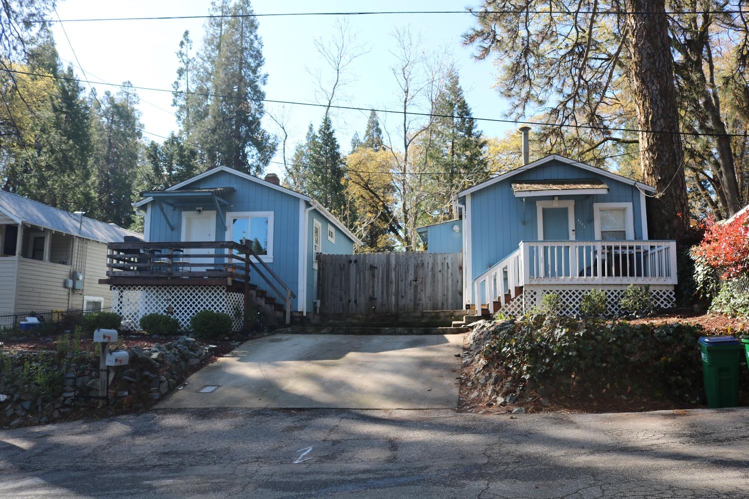 a view of a wooden house with a yard and large trees