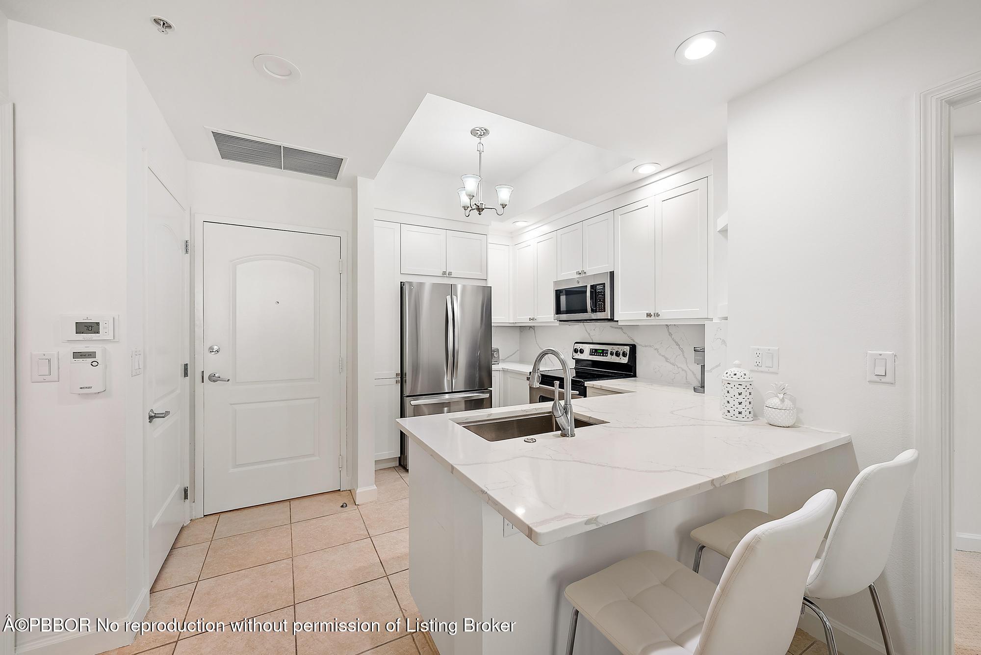 a kitchen with a sink a refrigerator and white cabinets