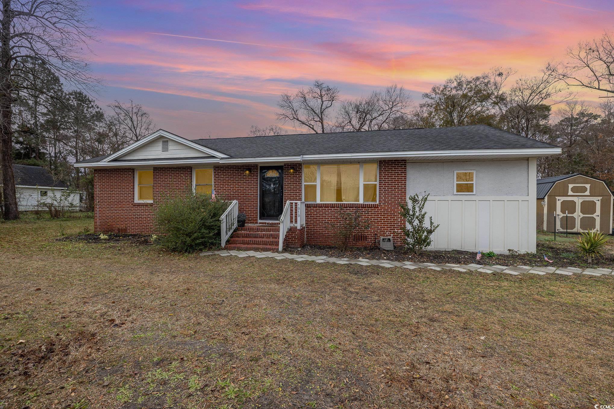 Ranch-style house featuring a lawn and a storage u