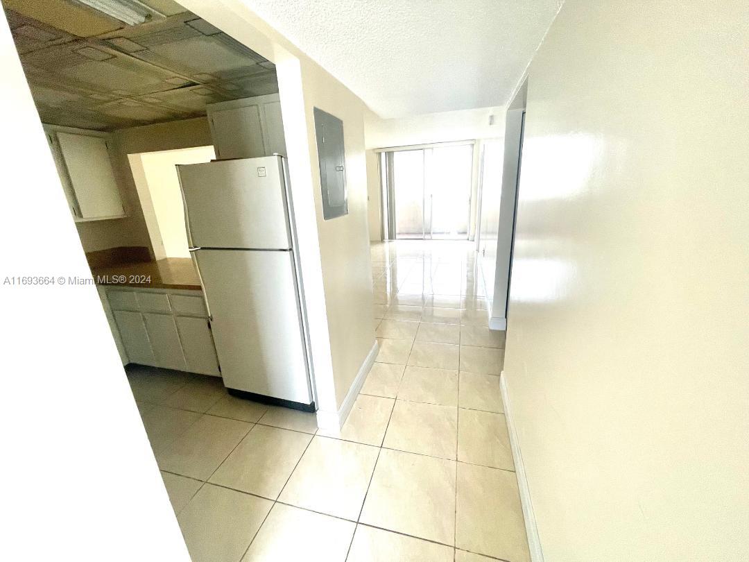 a view of a refrigerator in kitchen and an empty room