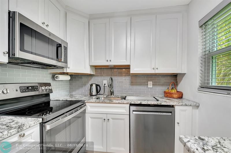 a kitchen with stainless steel appliances granite countertop a sink stove and microwave