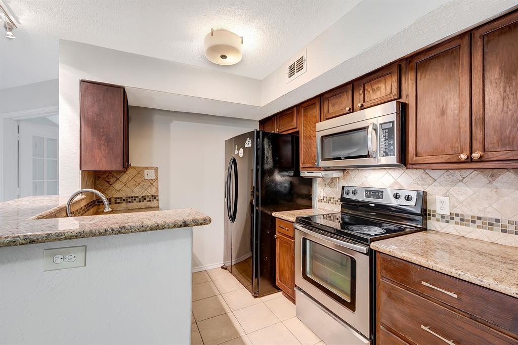 a kitchen with stainless steel appliances granite countertop a sink stove microwave and refrigerator