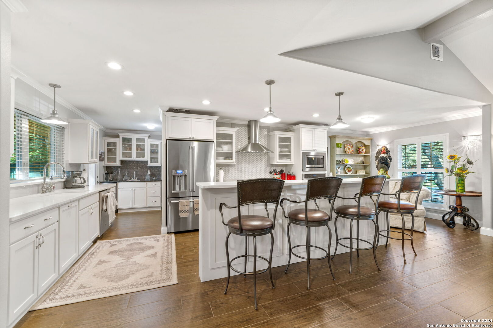 a kitchen with stainless steel appliances kitchen island granite countertop a dining table chairs and white cabinets