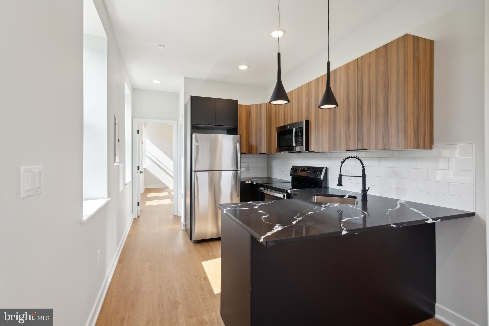 a kitchen with stainless steel appliances granite countertop a sink a stove and a refrigerator