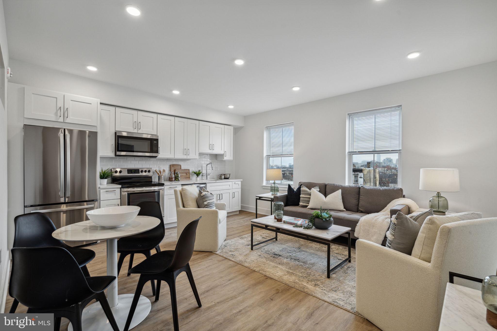 a living room with stainless steel appliances furniture a dining table and kitchen view