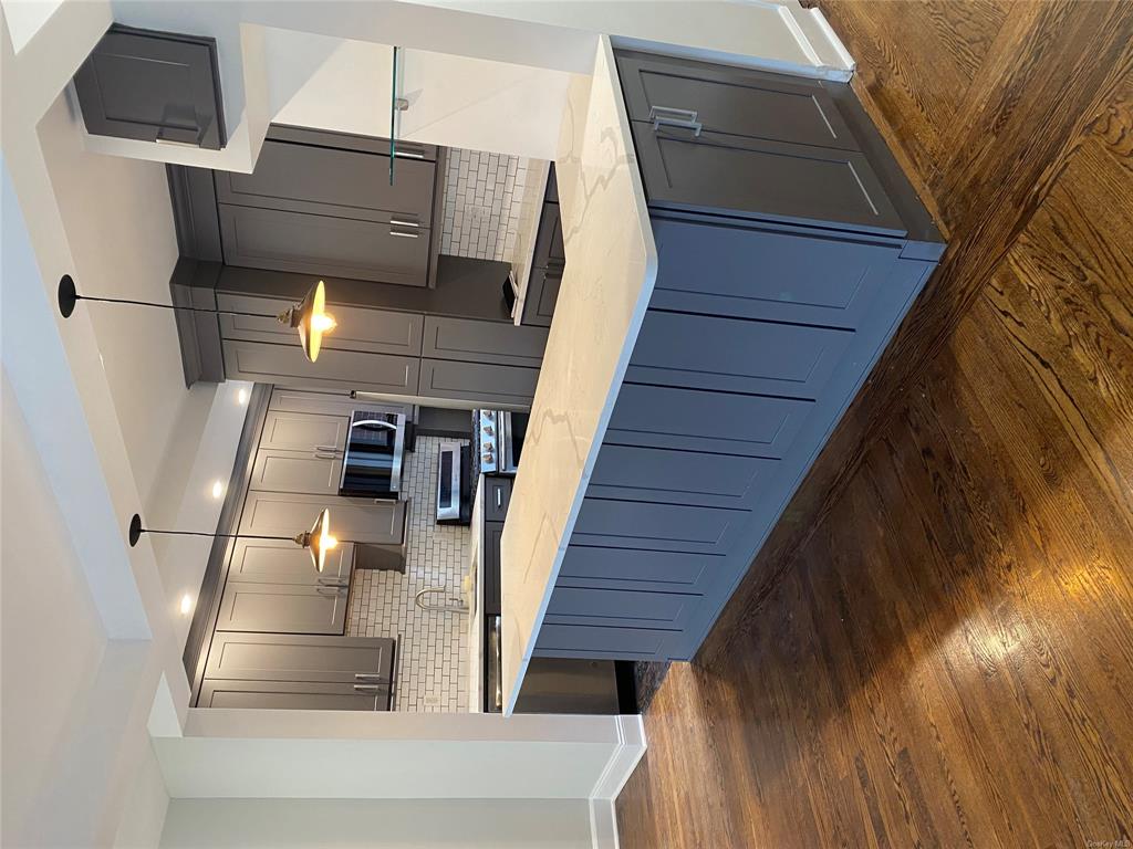 Kitchen featuring pendant lighting, dark hardwood / wood-style flooring, light stone countertops, and range