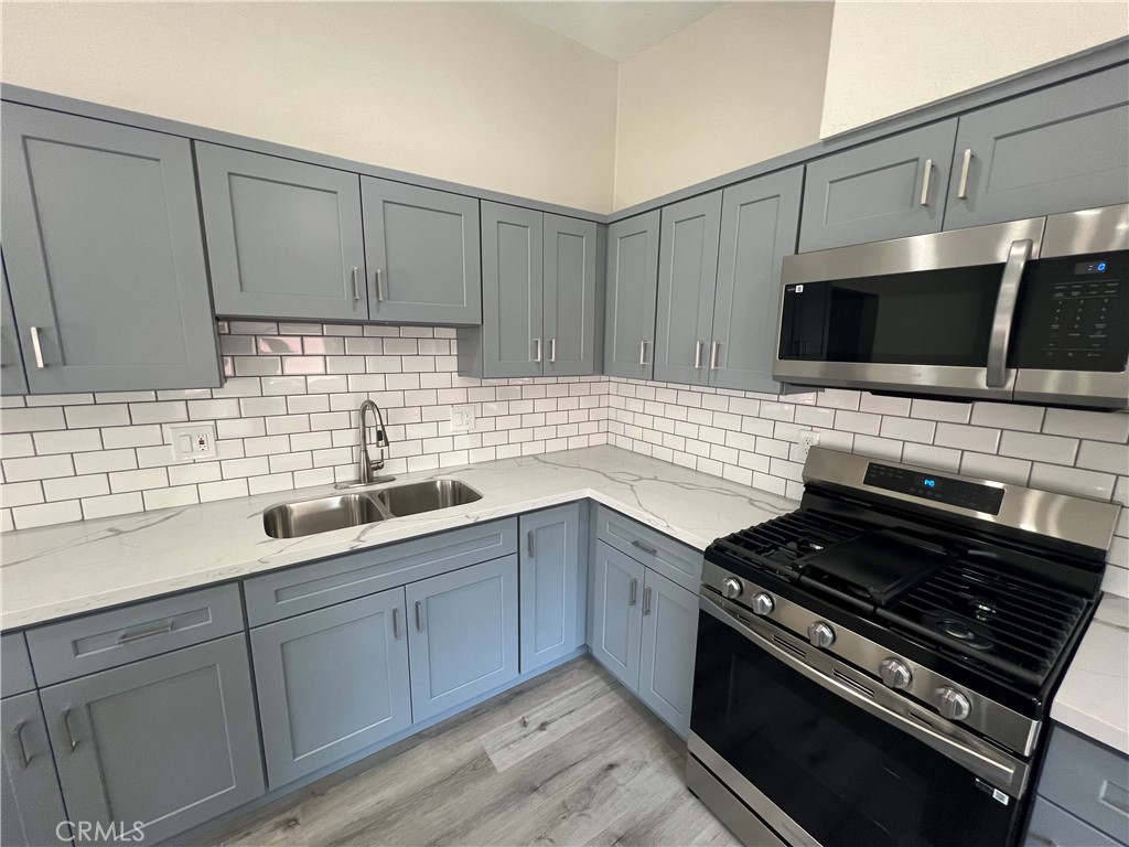 a kitchen with sink a microwave a stove and cabinets