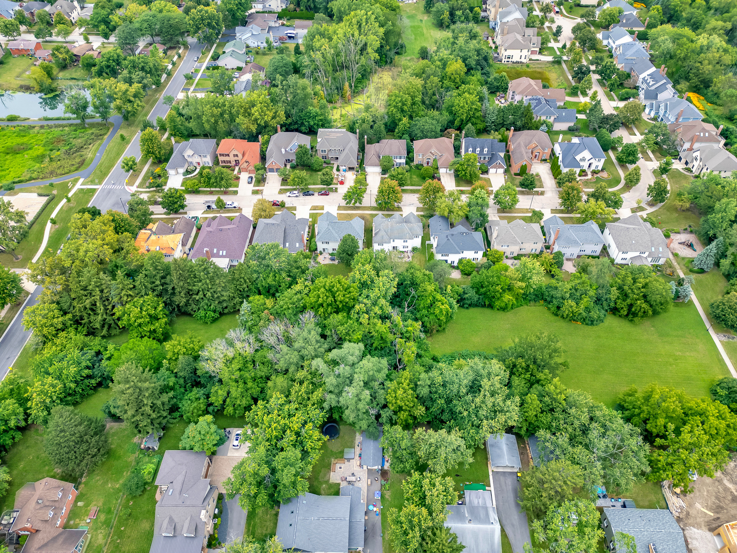 an aerial view of residential houses with outdoor space and trees all around