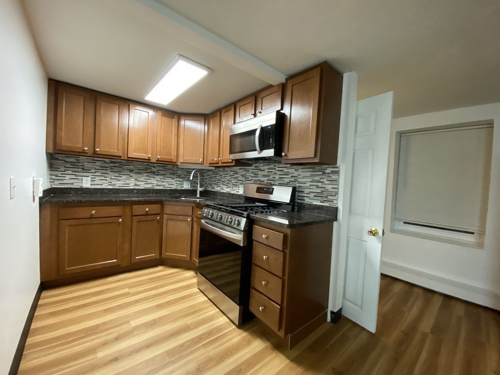 a kitchen with stainless steel appliances granite countertop wooden cabinets and a stove top oven