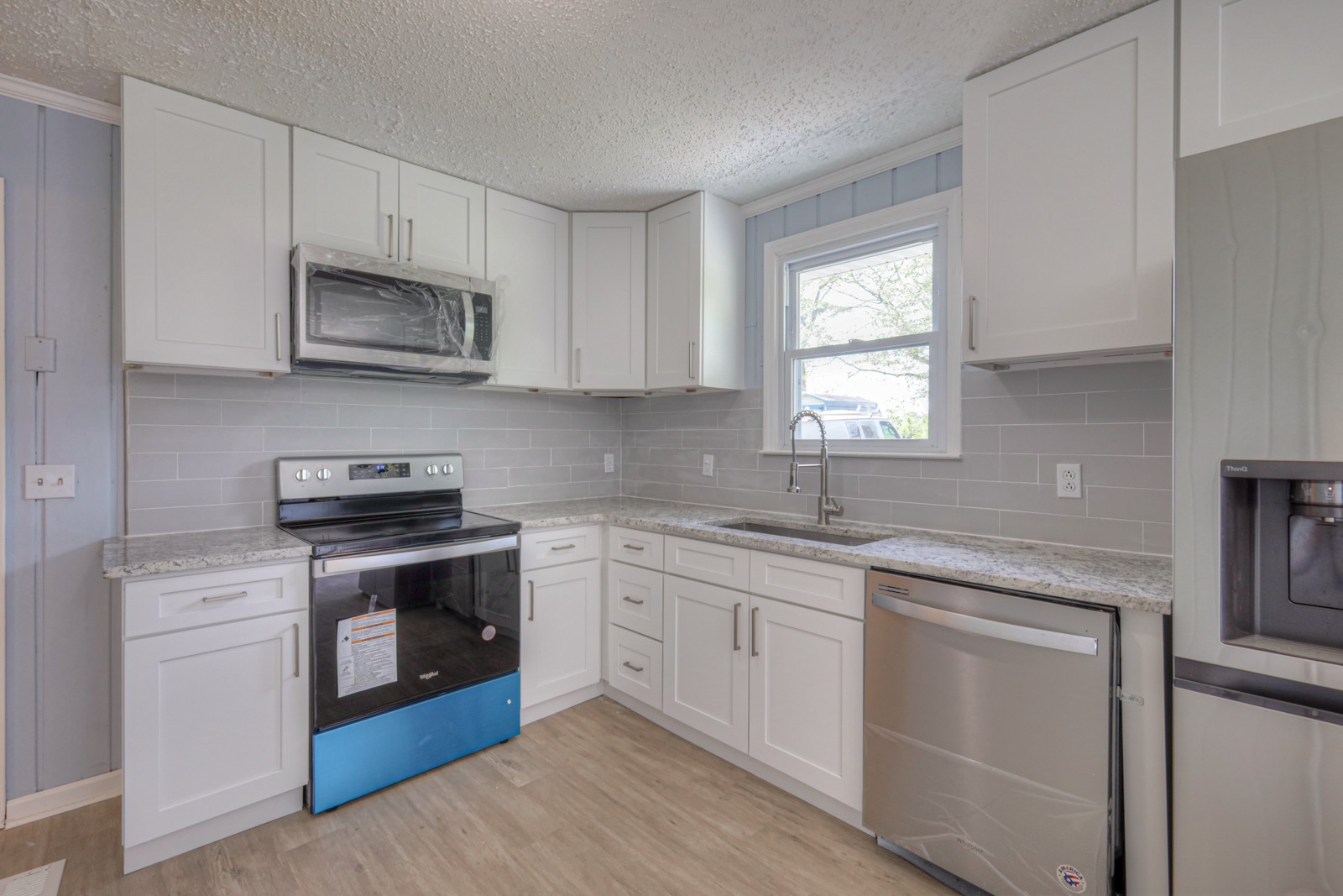 a kitchen with stainless steel appliances granite countertop white cabinets a sink and a stove